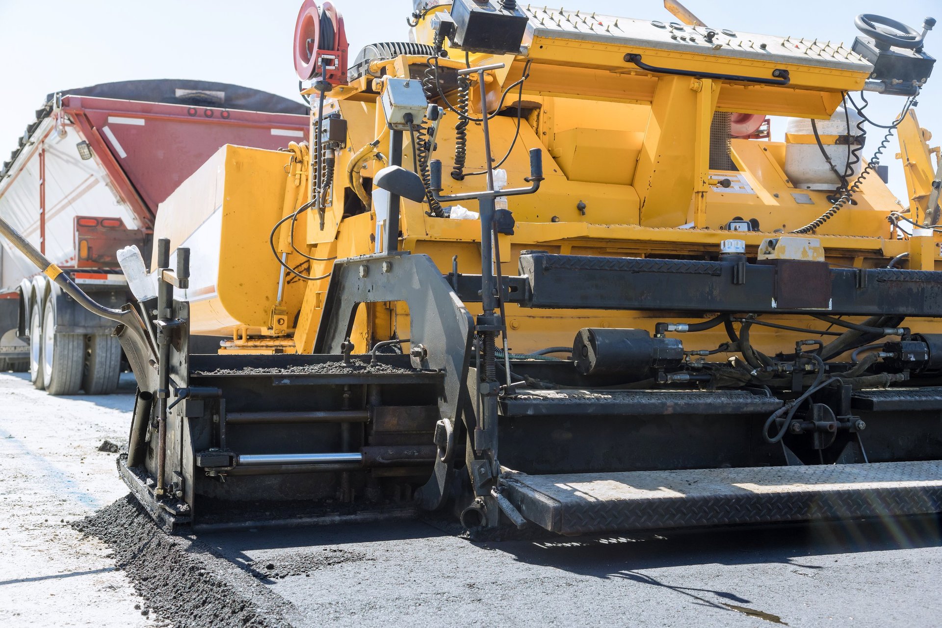 Highway concrete paver laying fresh bitumen asphalt on gravel base