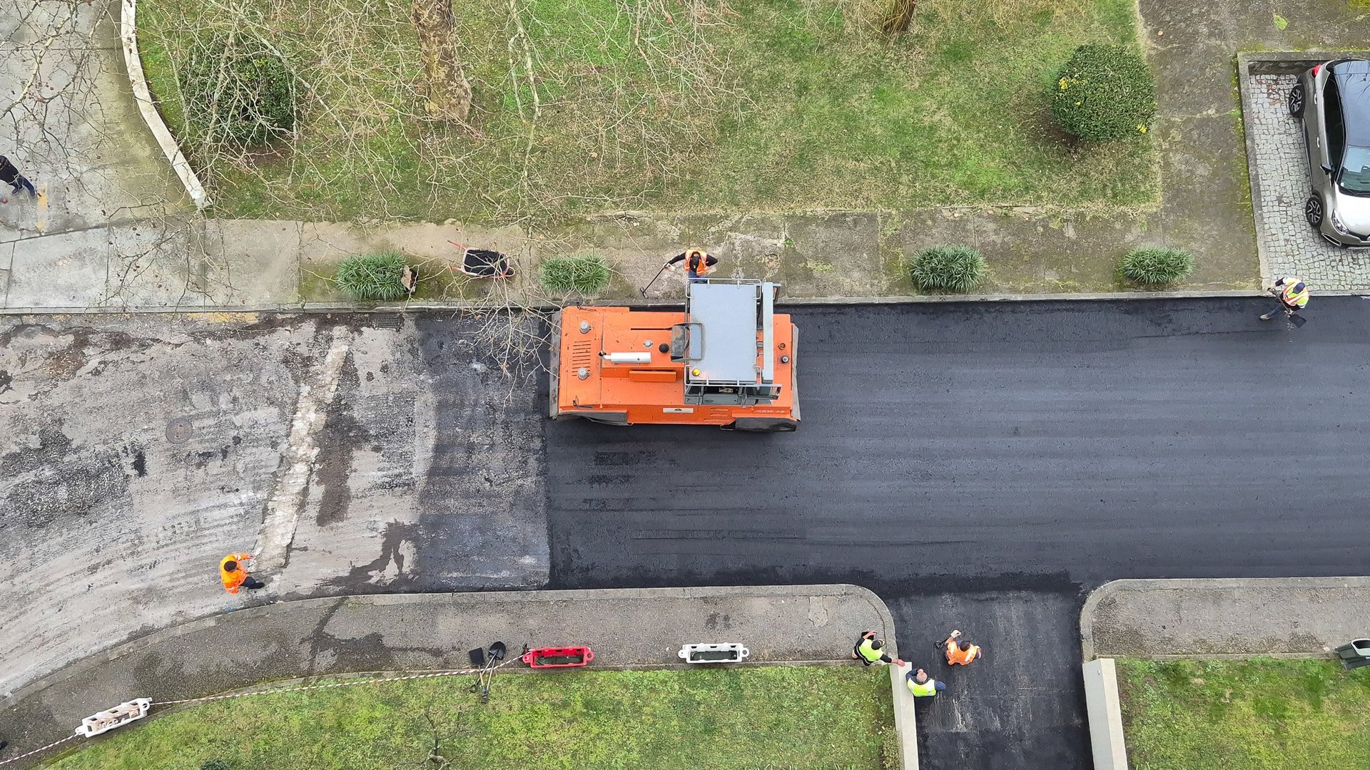 Workers repave public road with fresh asphalt using heavy machinery