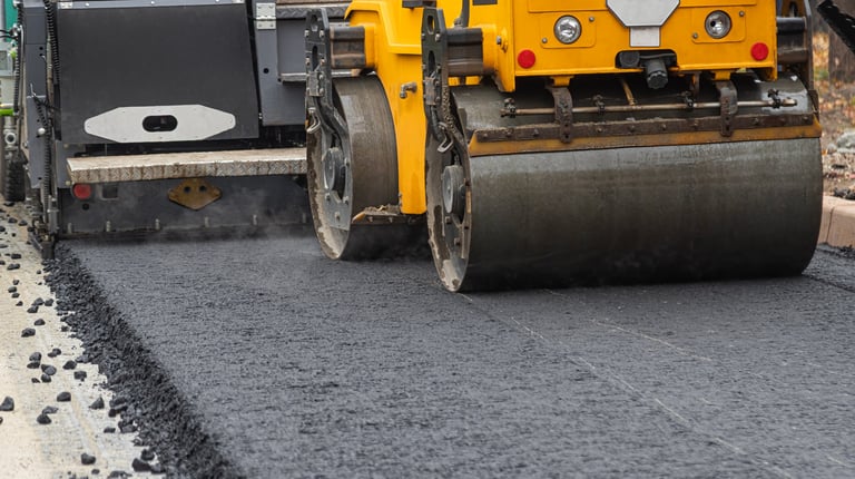 Professional paving with heavy roller creating smooth asphalt surface
