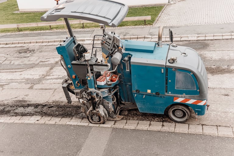 Road milling machine removing old asphalt near a curb during street maintenance in Leander, TX — asphalt resurfacing and repair by Austin Premier Paving